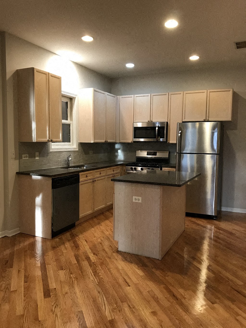 a large kitchen with stainless steel appliances and wooden floors