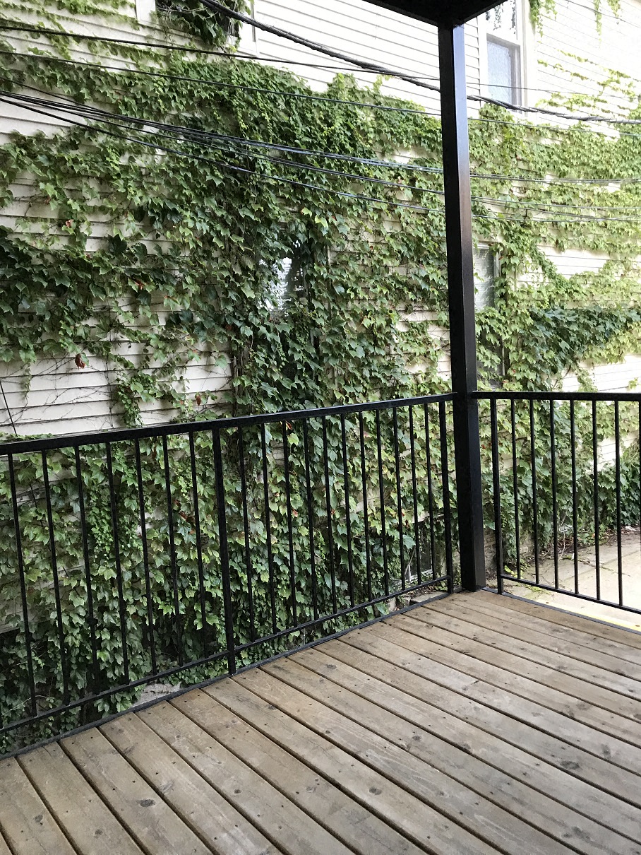 a balcony with a wooden floor and a black railing
