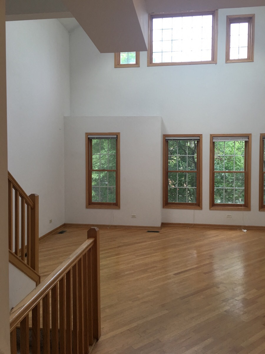 an empty living room with a hard wood floor and windows