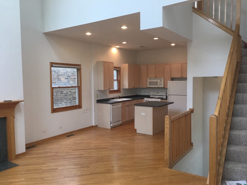 an empty living room with a staircase and a kitchen