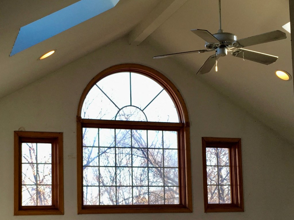 an arched window in a church with a ceiling fan