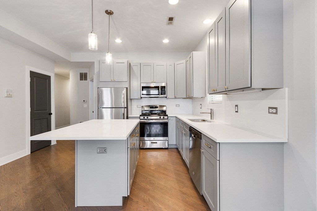 a large white kitchen with stainless steel appliances and white counters