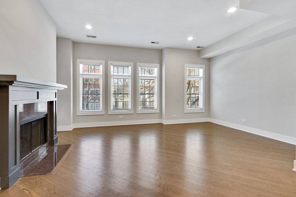 an empty living room with a fireplace and windows