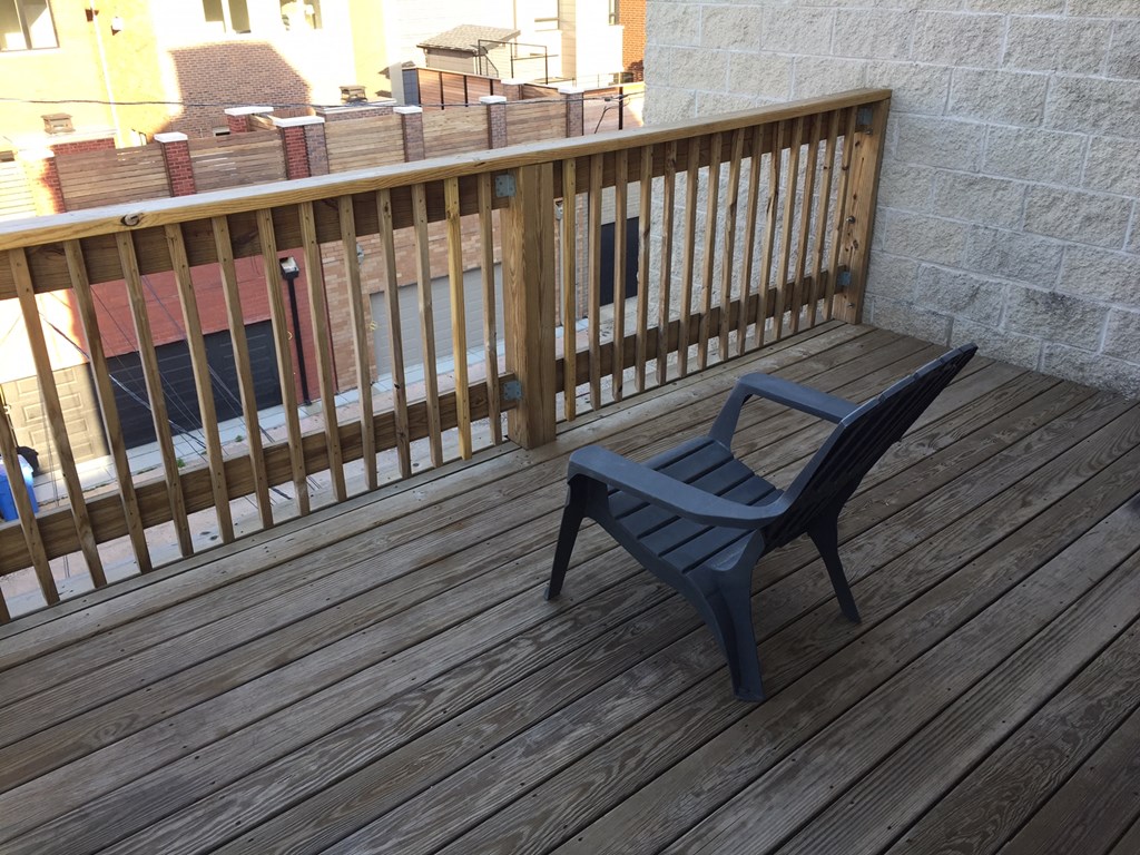 a balcony with a blue chair and a wooden railing