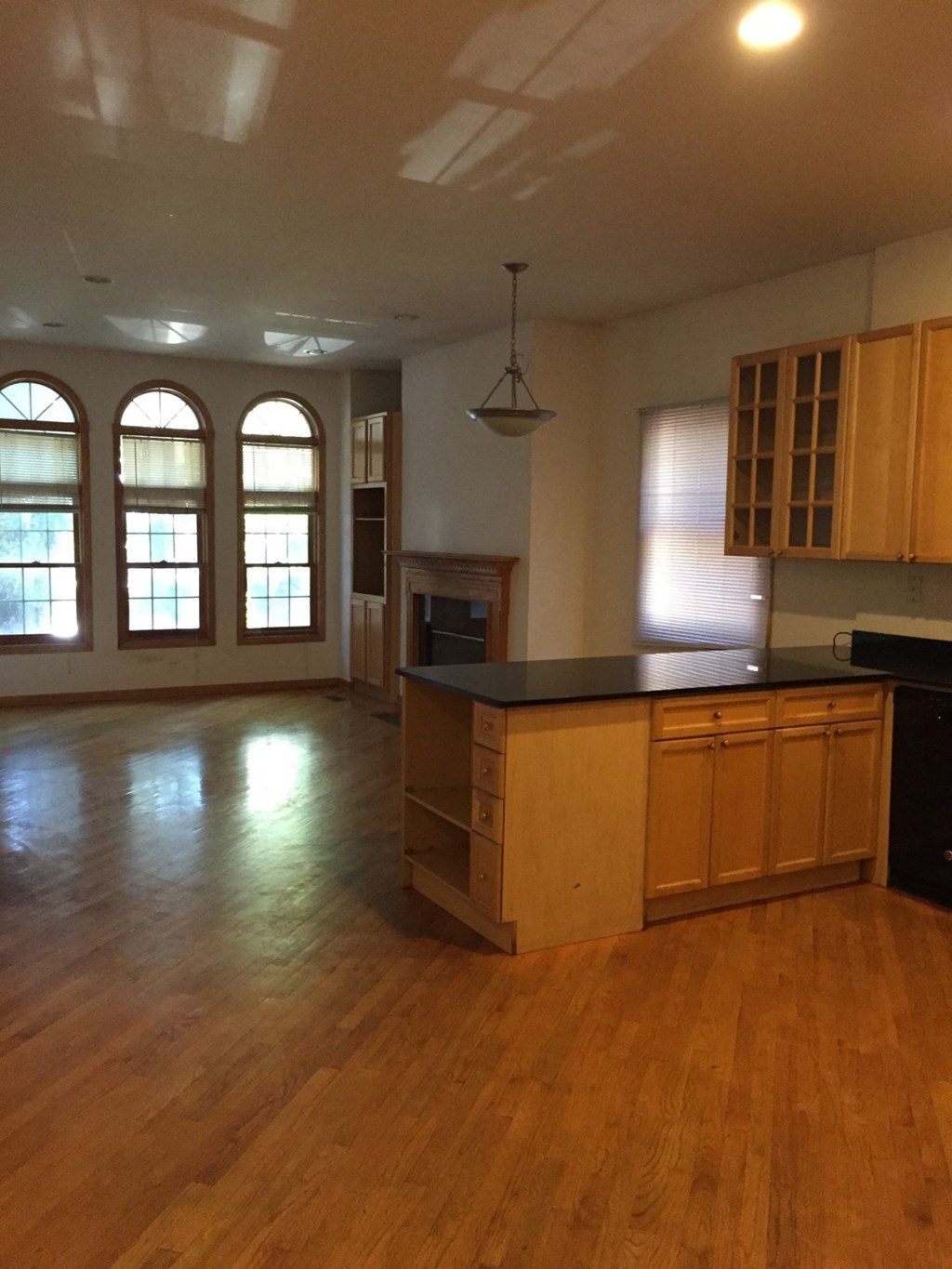 an empty kitchen and living room with wood flooring and windows