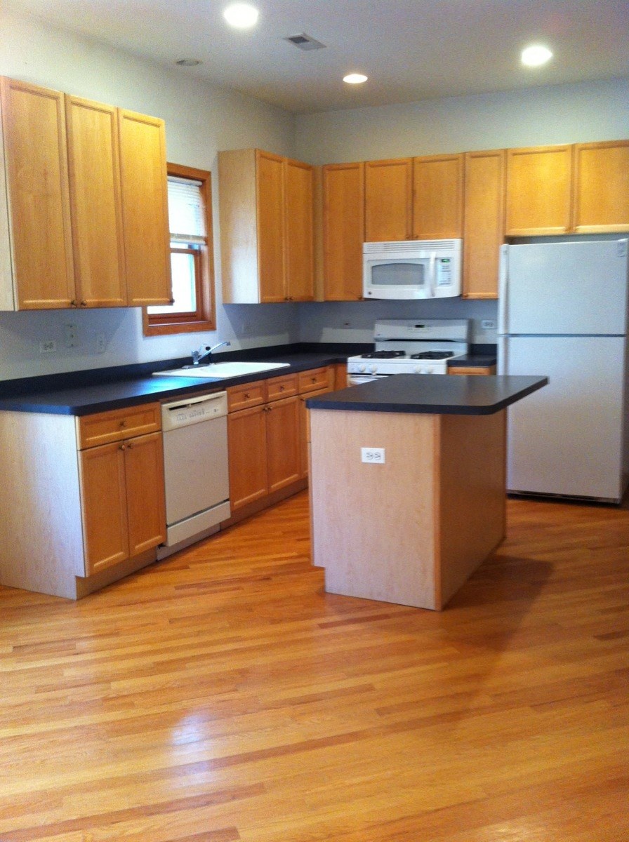 an empty kitchen with wooden cabinets and white appliances
