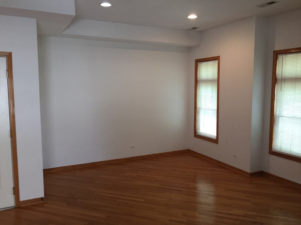 an empty room with wooden floors and two windows
