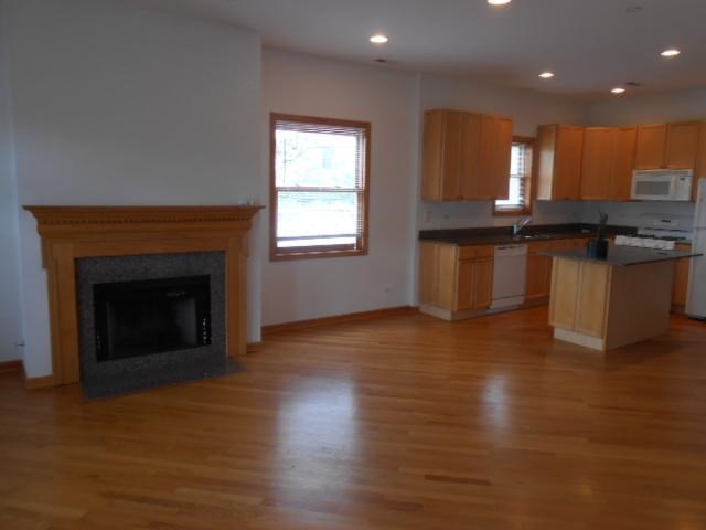 an empty living room with a fireplace and a kitchen