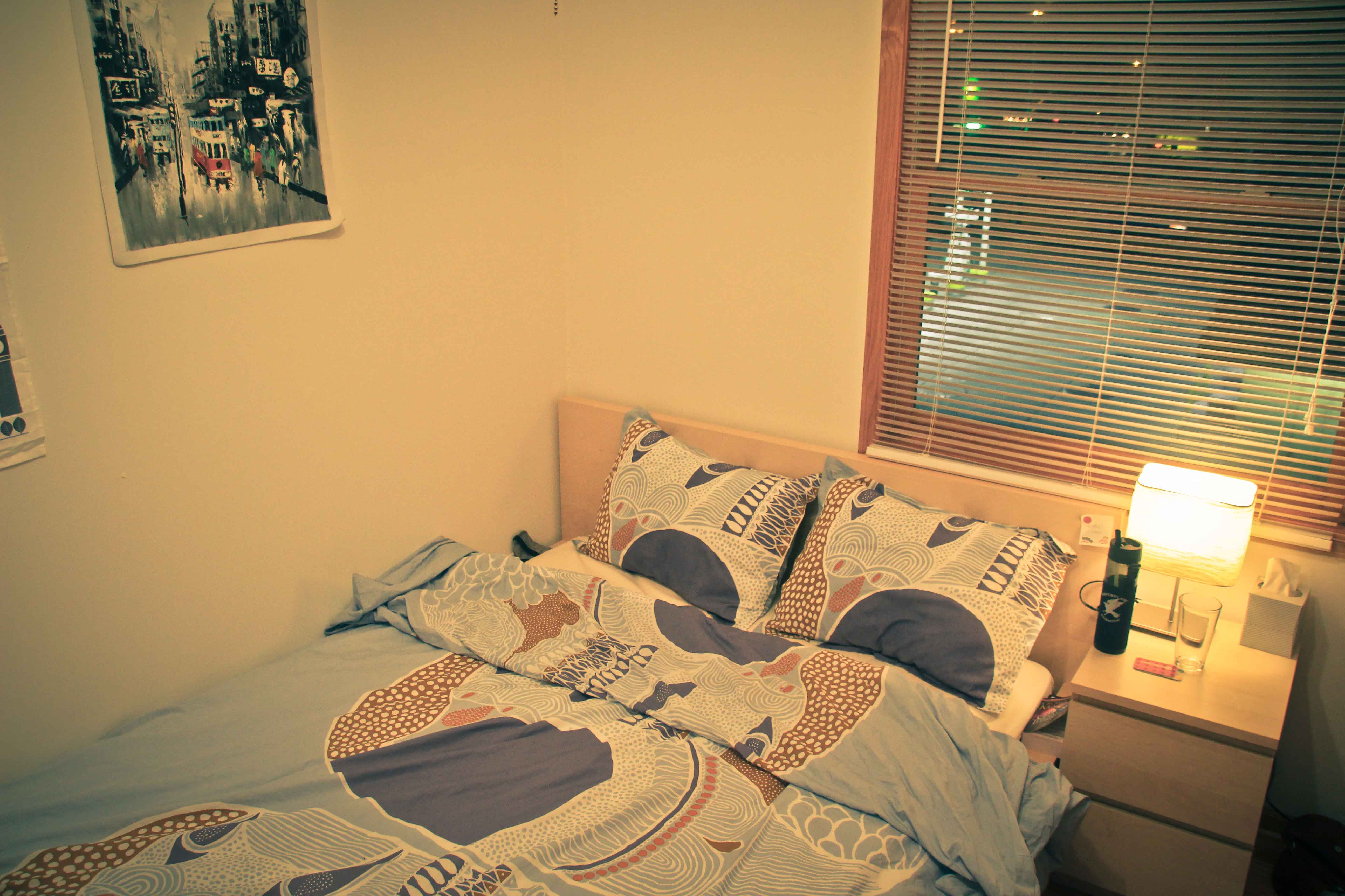 a bedroom with a bed with pillows and a lamp and a window