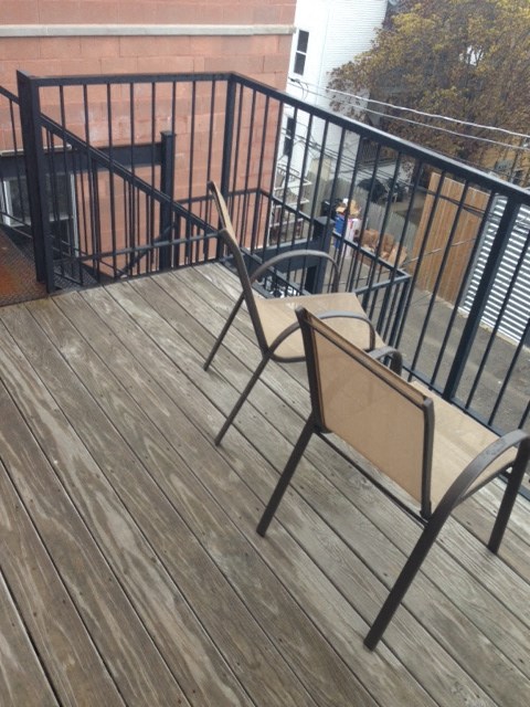 a wooden deck with two chairs and a railing