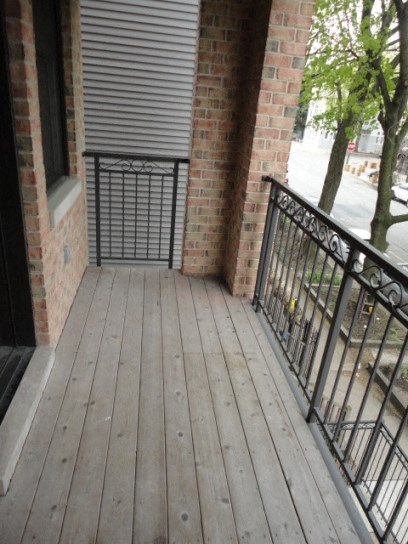 a balcony with a wooden floor and a brick building