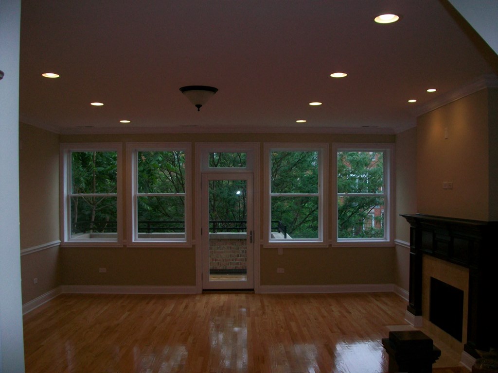 an empty living room with windows and a hard wood floor