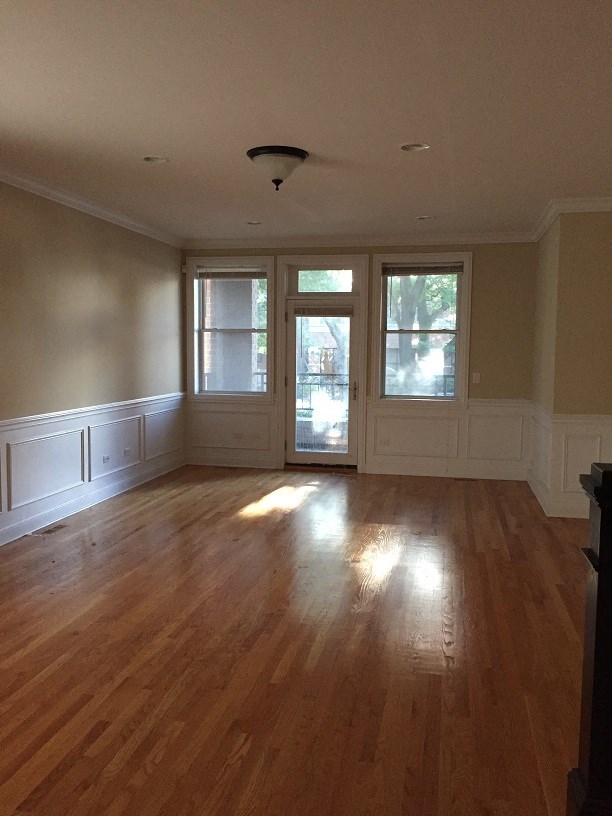 an empty living room with a hard wood floor and windows