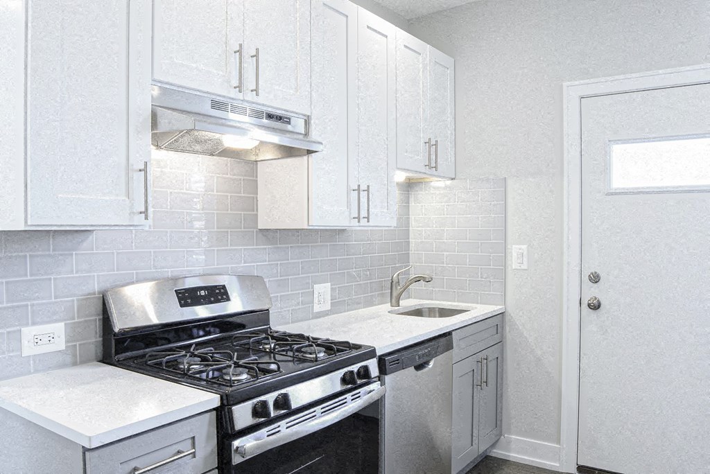 a kitchen with white cabinets and a stove and a sink