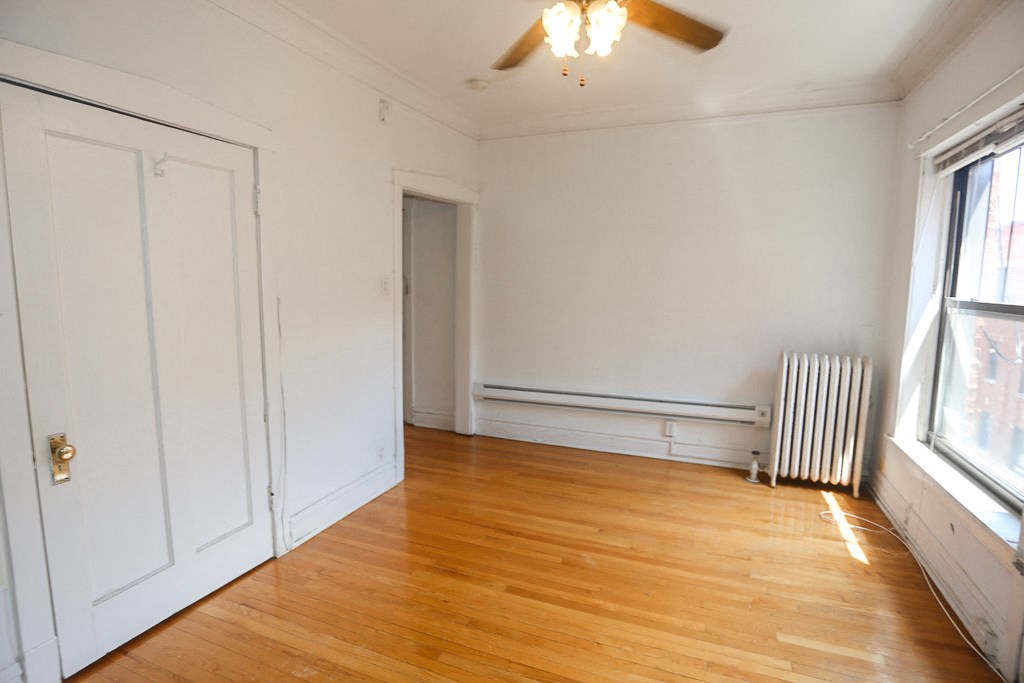a living room with white walls and wood floors and a ceiling fan