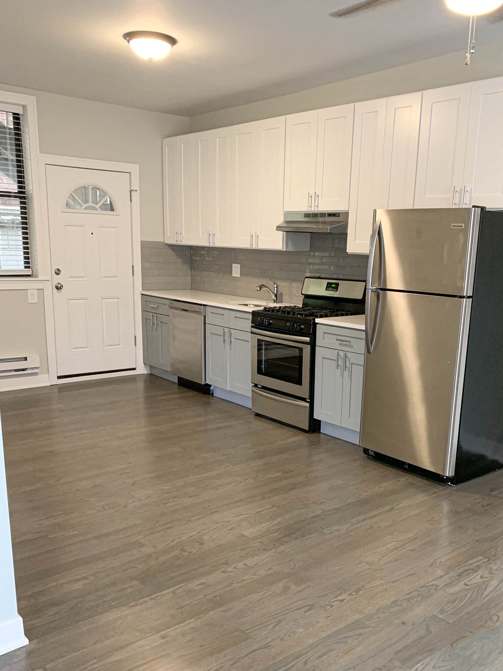 a kitchen with white cabinets and a stainless steel refrigerator