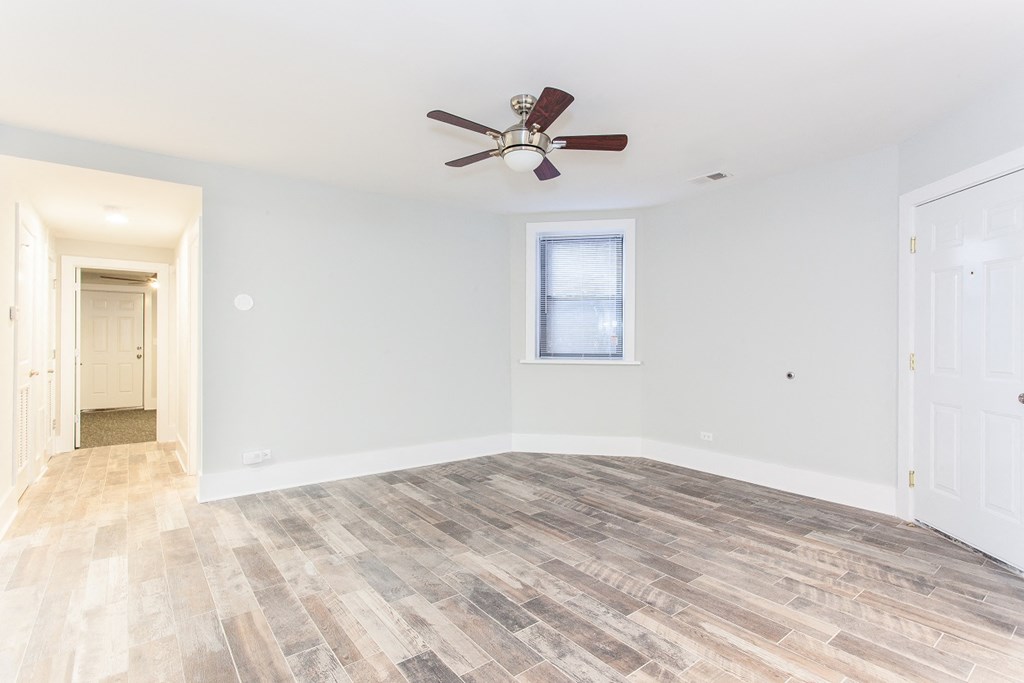 an empty living room with a ceiling fan and white walls