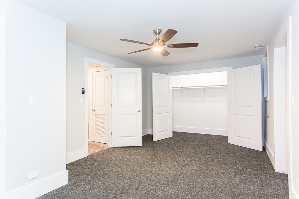 an empty bedroom with a ceiling fan and a closet