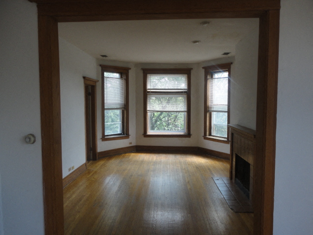 an empty living room with a fireplace and three windows