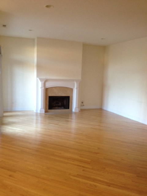 an empty living room with a fireplace and wooden floors