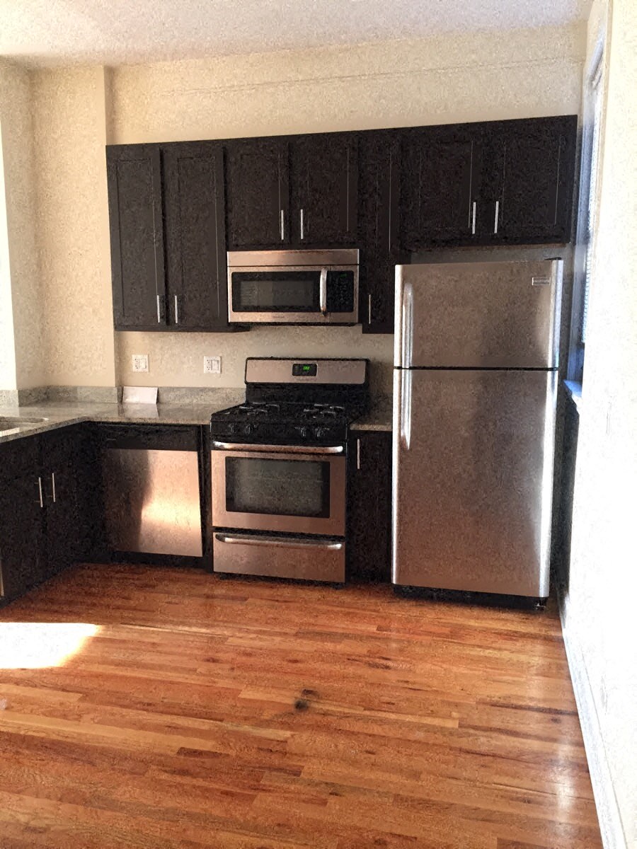 a kitchen with stainless steel appliances and wooden floors