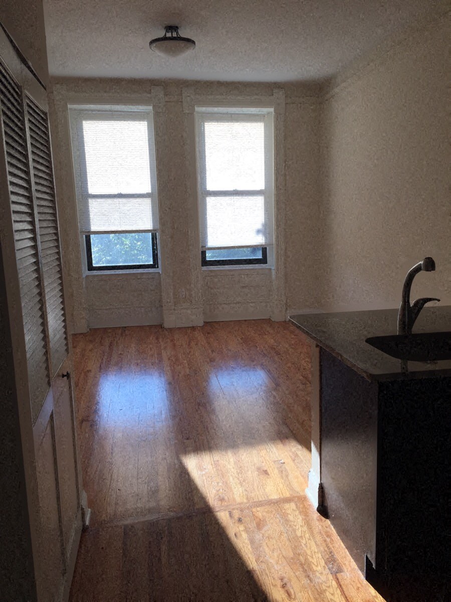 a living room with a hard wood floor and three windows