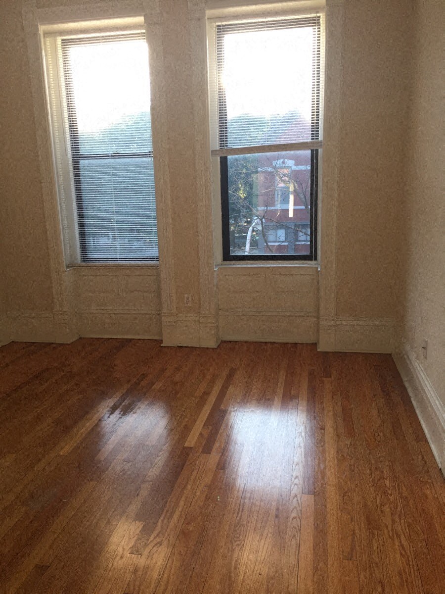 a living room with a hard wood floor and two windows