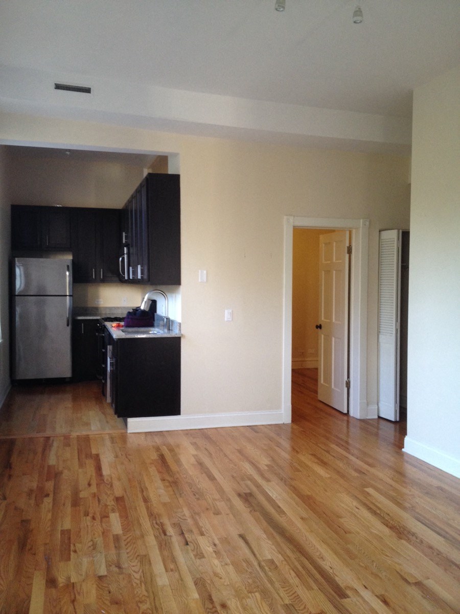 an empty living room and kitchen with wood floors