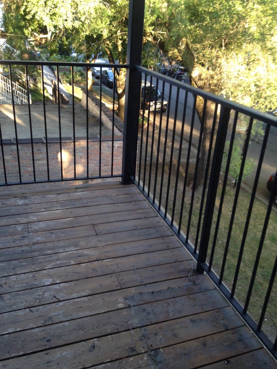 a balcony with a black metal railing and a tree