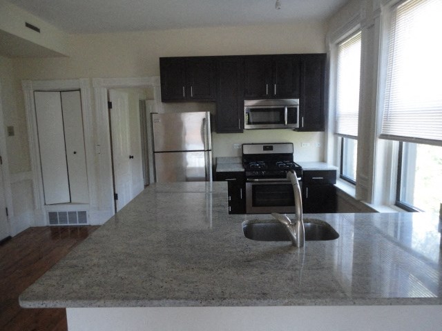 an empty kitchen with black cabinets and stainless steel appliances
