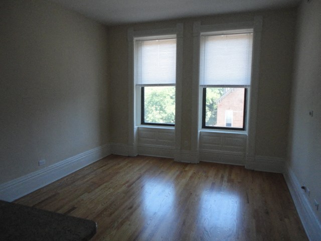 a living room with two windows and a wooden floor