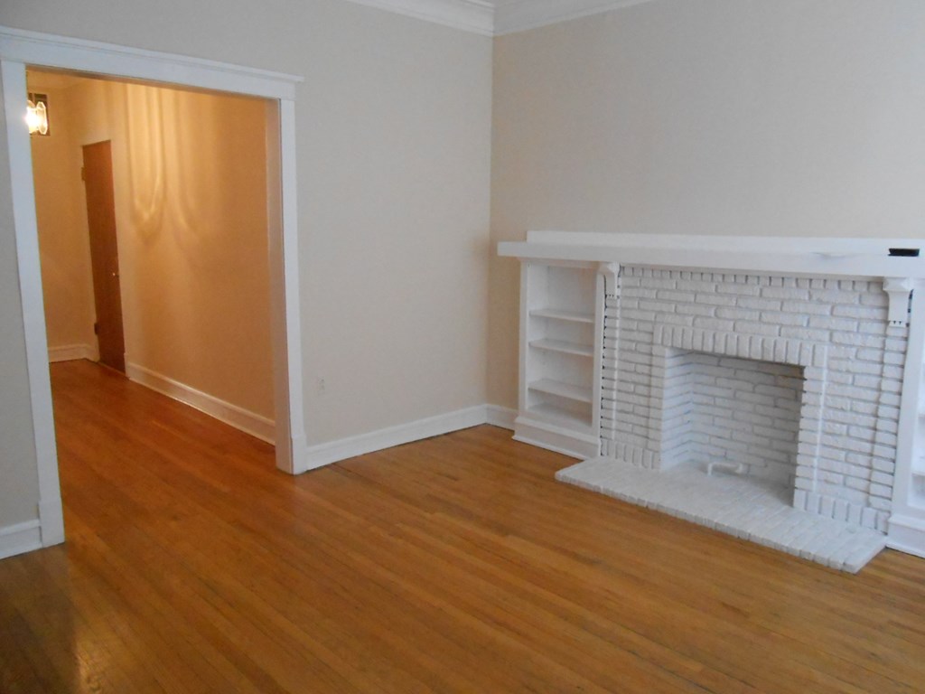 a living room with a brick fireplace and wooden floors