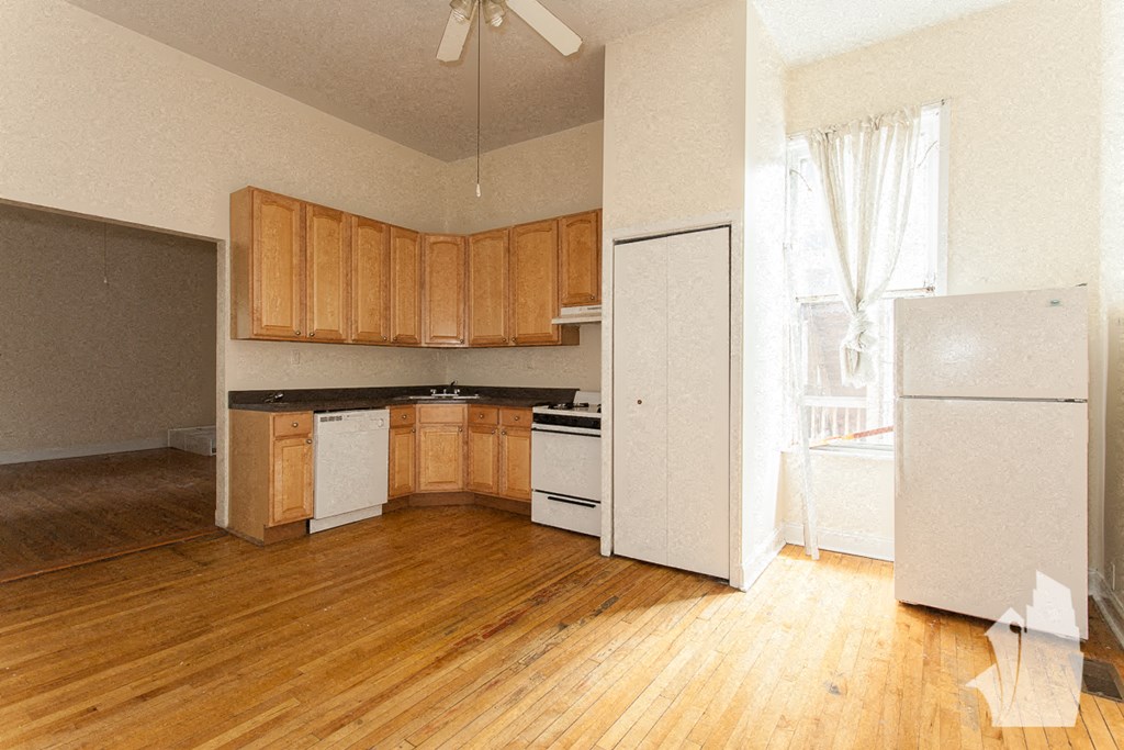 an empty kitchen with wooden floors and a refrigerator