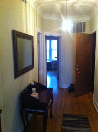 a hallway with a table and a mirror and a door to a bedroom