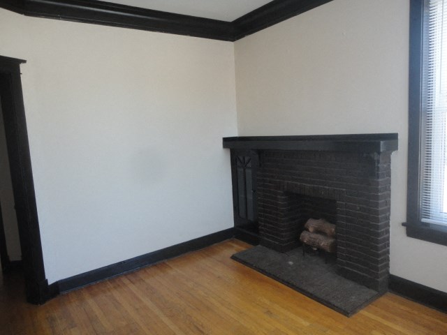 the living room has a brick fireplace and wooden floors