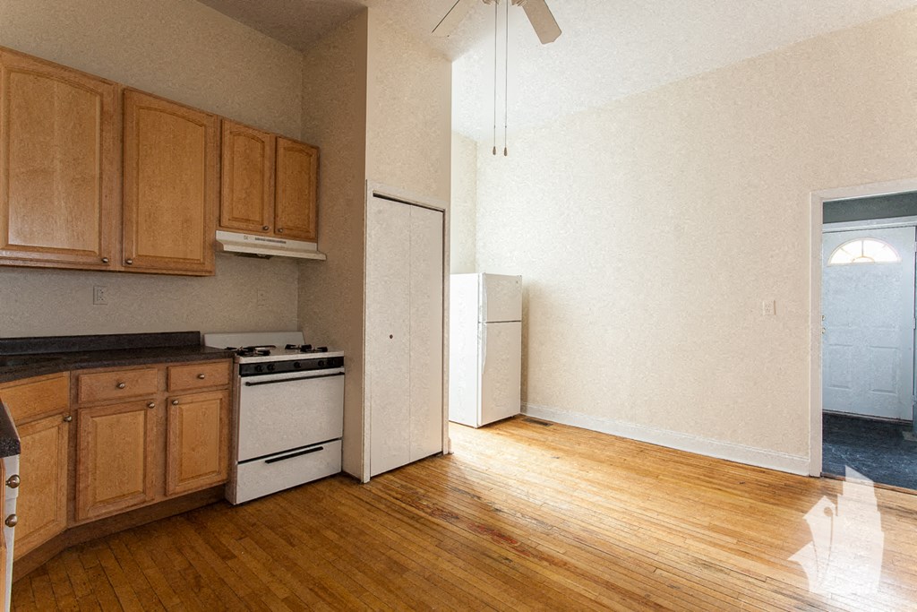 an empty kitchen with wood floors and a white refrigerator