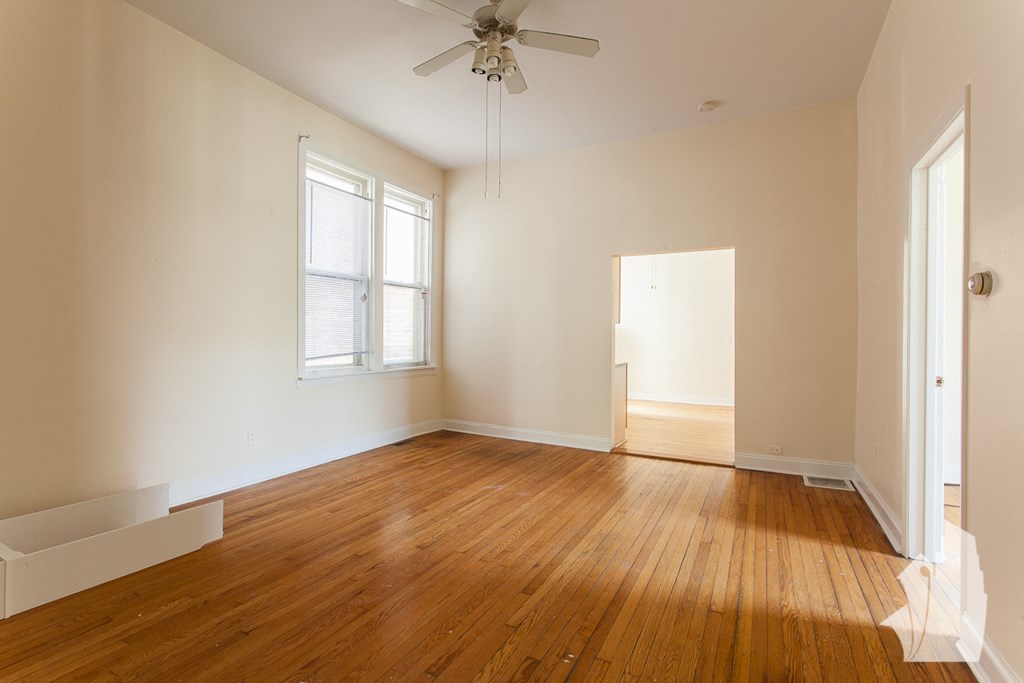 an empty living room with wood floors and a ceiling fan