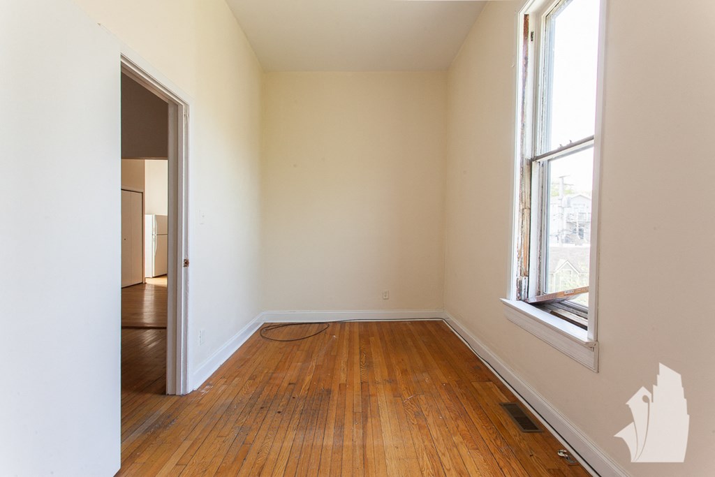 an empty room with wooden floors and a window