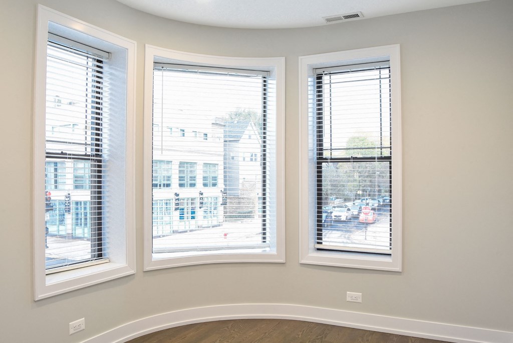 three windows in a corner of a room with a city view