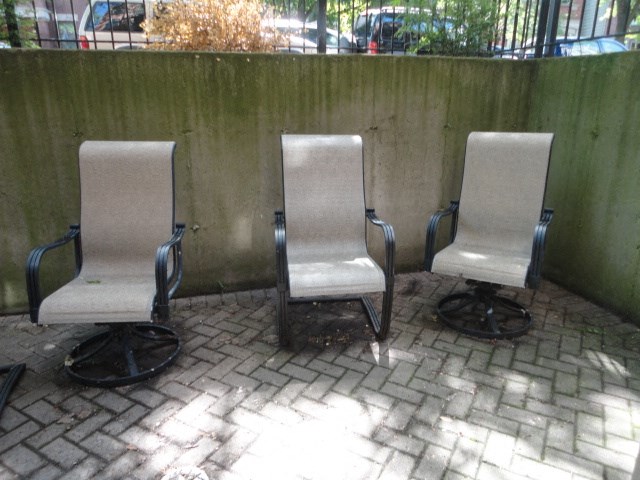 three chairs sitting on a brick sidewalk next to a wall