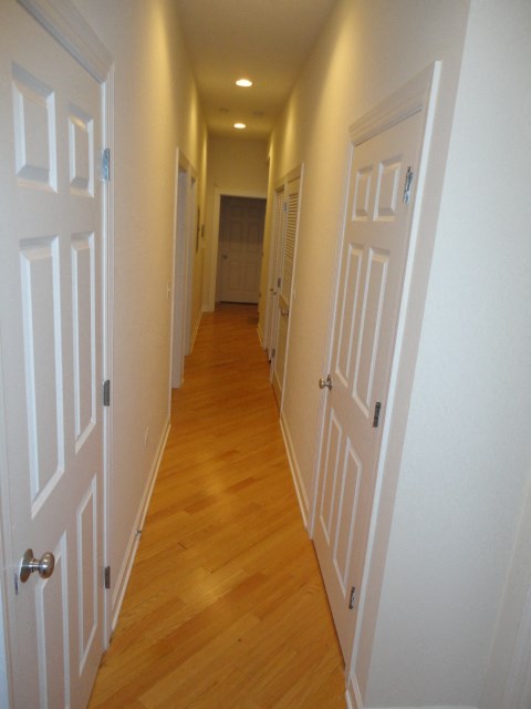 a long hallway with white doors and wood floors