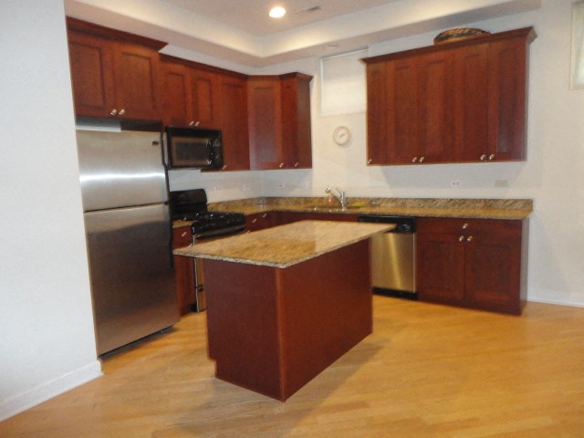 an empty kitchen with stainless steel appliances and wooden cabinets