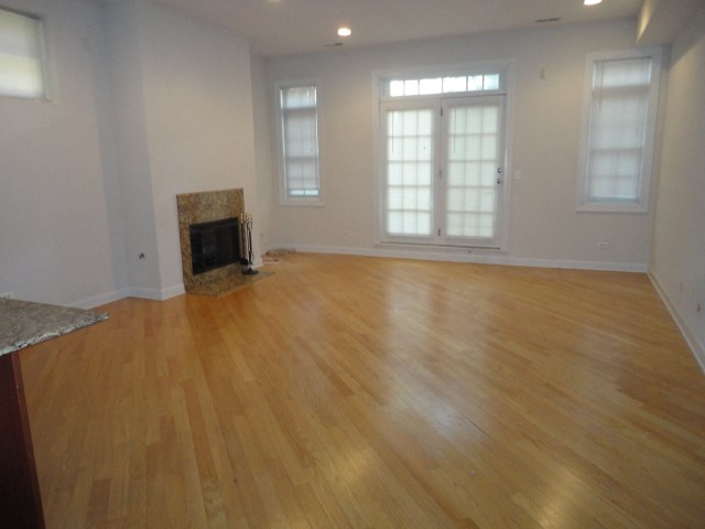 an empty living room with a fireplace and wooden floors
