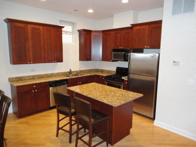 a kitchen with an island and a stainless steel refrigerator