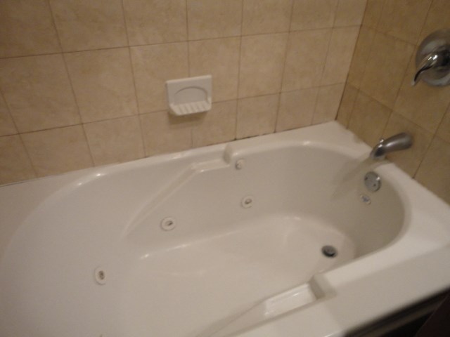 a bath tub in a small bathroom with a tile wall and a shower