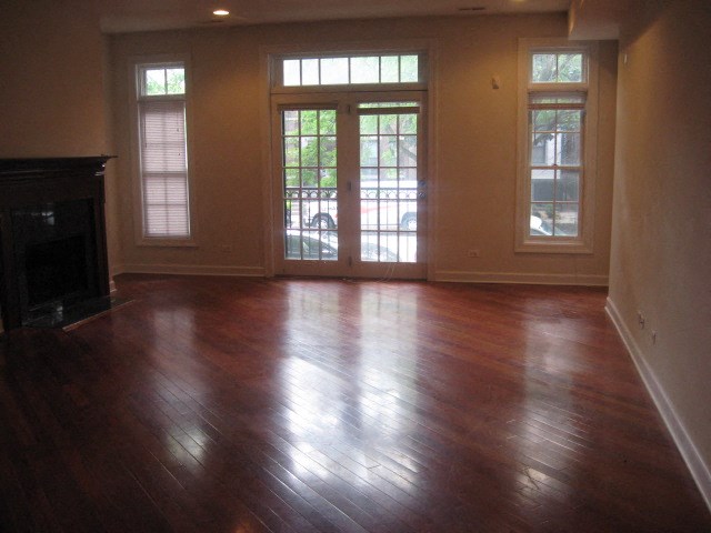 an empty living room with a fireplace and wooden floors