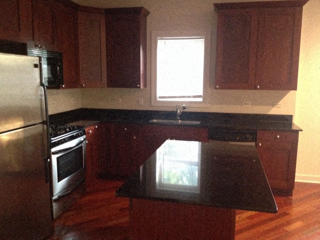 an empty kitchen with a black counter top