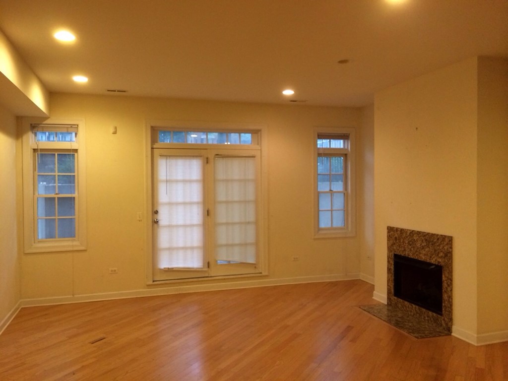 an empty living room with a fireplace and windows