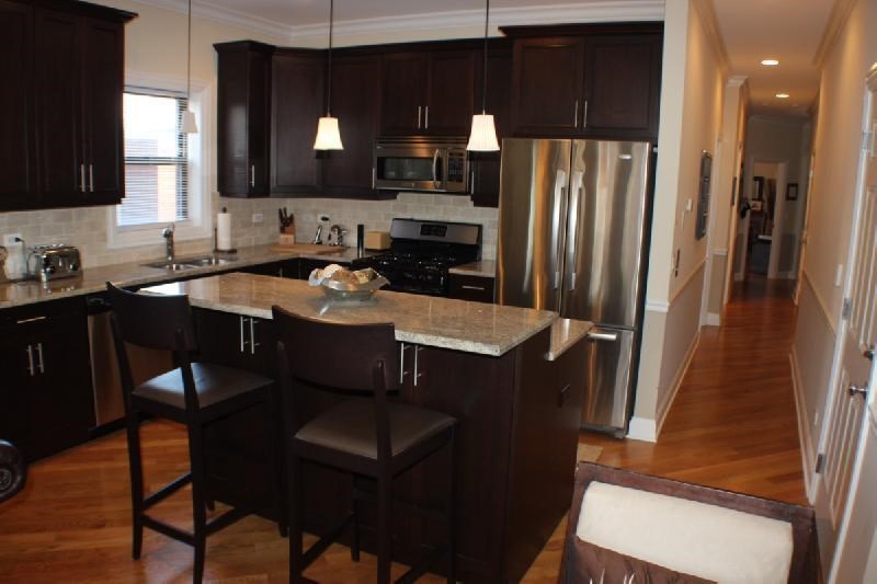 a kitchen with an island and a stainless steel refrigerator