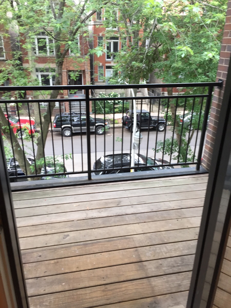 a balcony with a wooden floor and a view of a street